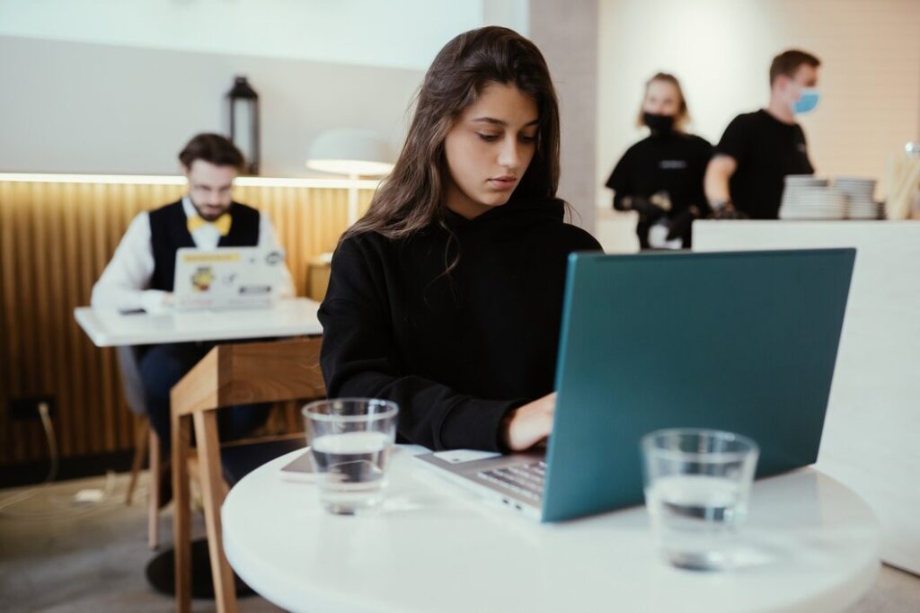 Woman using a portable laptop while working remotely in a cafe